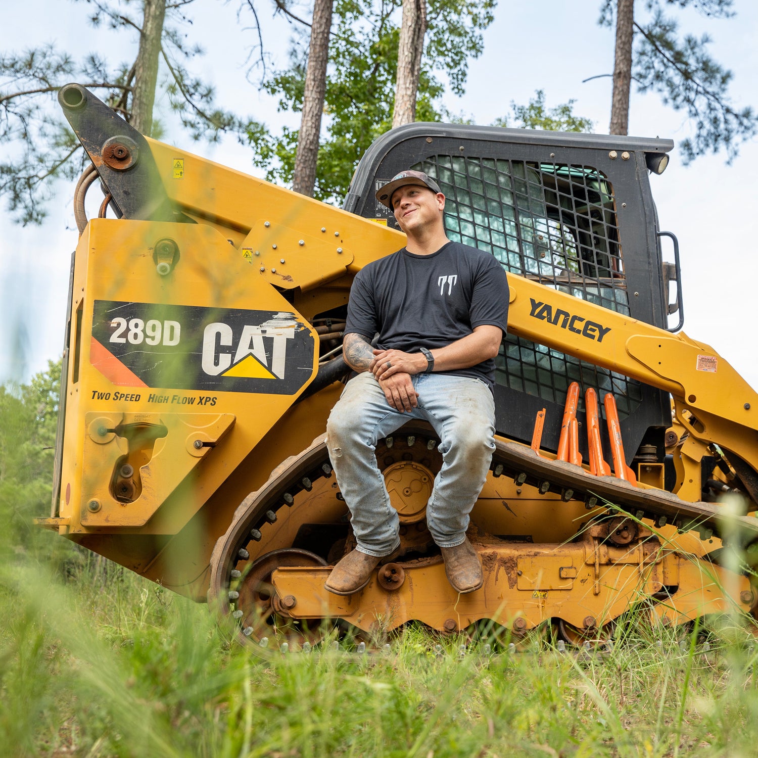 Man in black shirt sitting on yellow CAT 289D compact track loader outdoors