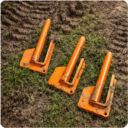 Three orange construction safety cones lying on their sides on grass beside dirt with tire tracks