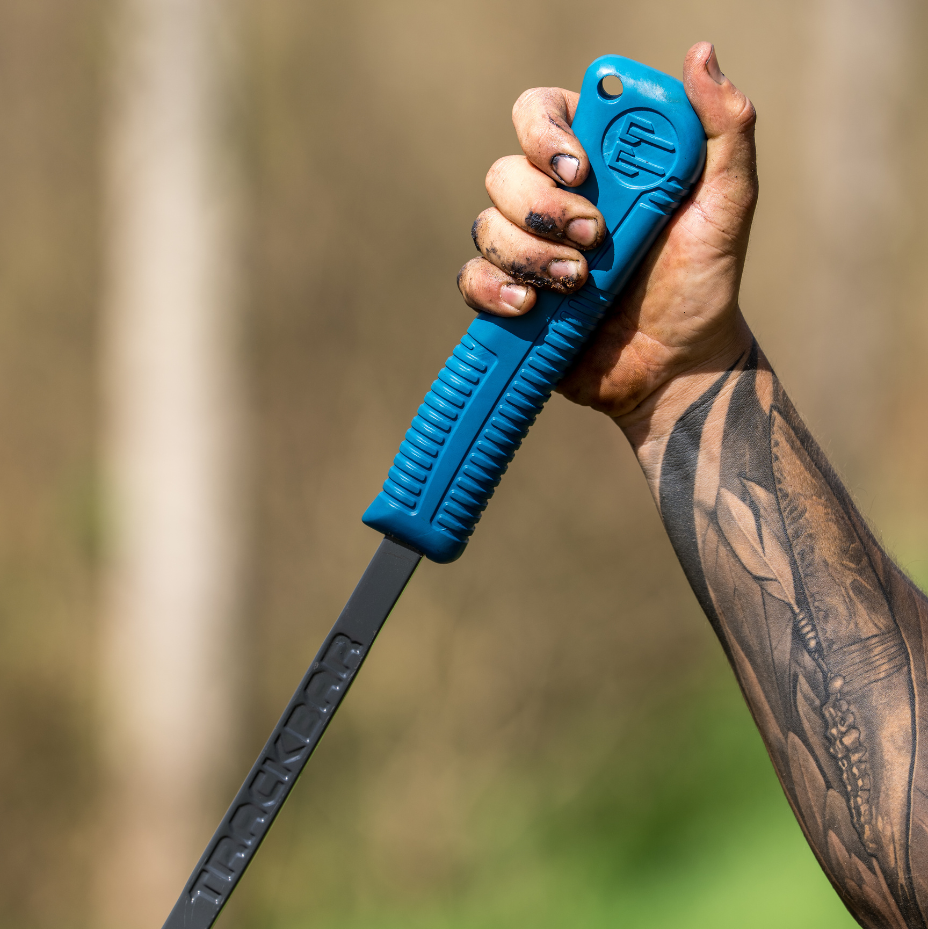 Tattooed hand gripping a blue ProBar tool handle outdoors in a forest setting
