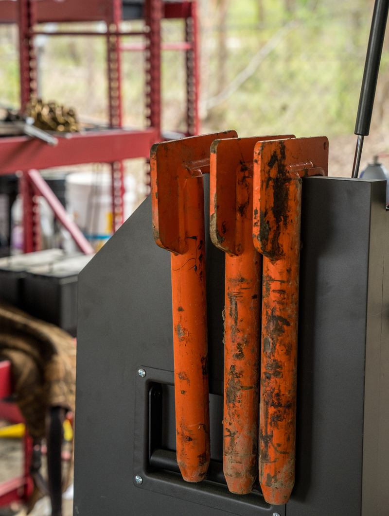 Three dirty orange trackbars mounted on a gray metal panel in a workshop