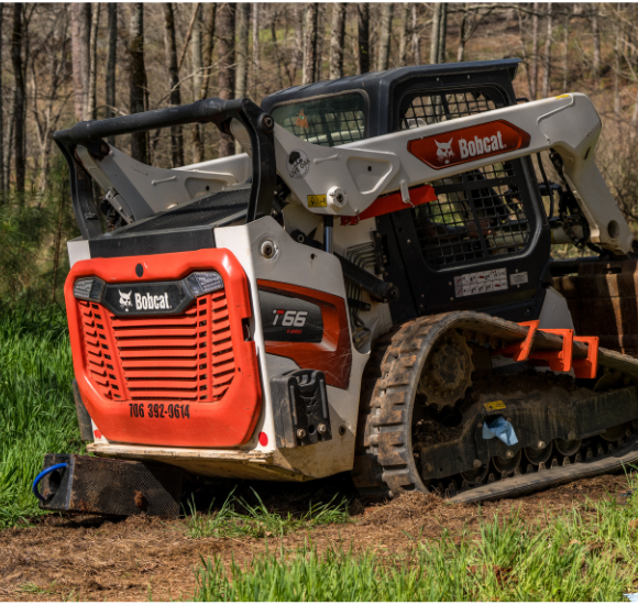 Bobcat T66 compact track loader with red and white body working on dirt terrain near trees