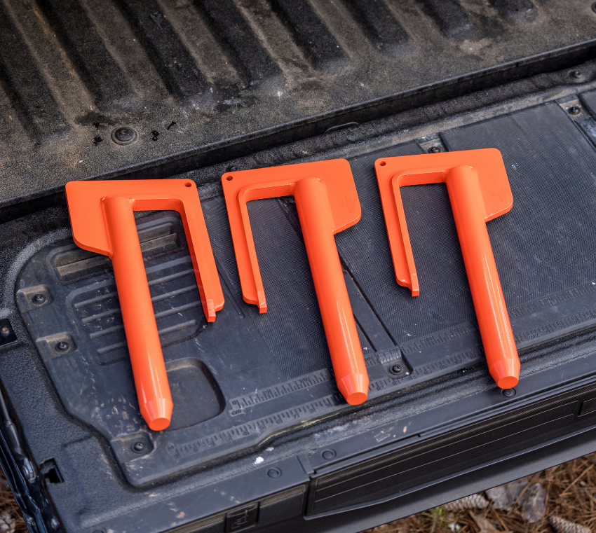 Three orange plastic track bar tools laid on a black truck bed liner