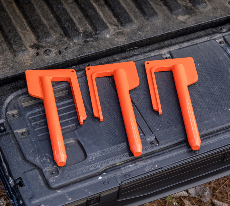 Three orange plastic track bar tools laid on a black truck bed liner
